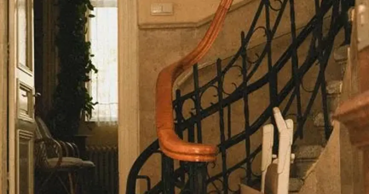 Monte-escalier à siège installé sur un escalier tournant à rampe en fer forgé