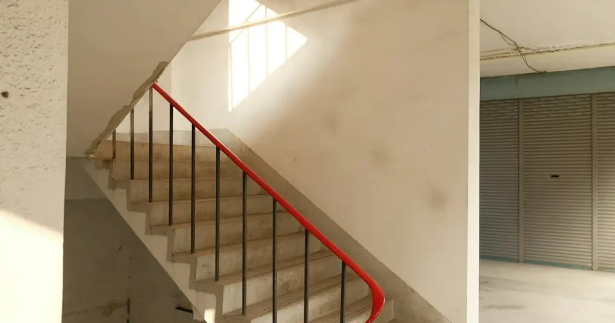 Cage d’escalier tournante à rampe rouge dans un immeuble ancien