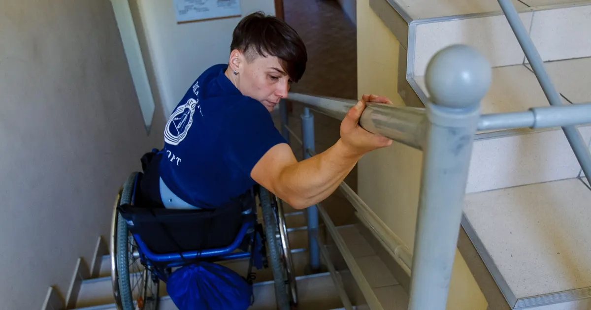 Personne en fauteuil roulant devant un escalier